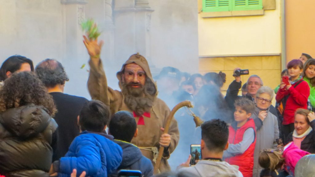 Sant Antoni kastar godis till barnen.